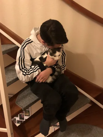 Paul sitting on the stairs hugging his cat